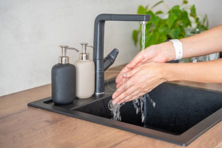 Woman washes hands and uses soap from reusable bottle. Eco-friendly lifestyle. High quality photo