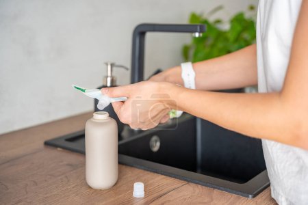 Eine Frau gießt Seife oder Waschmittel aus recycelten Verpackungen in eine Mehrwegflasche. Umweltfreundliches Lifestylekonzept. Hochwertiges Foto
