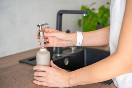 Eine Frau verwendet Seife oder Waschmittel in einer Mehrwegflasche. Umweltfreundlicher Lebensstil. Hochwertiges Foto