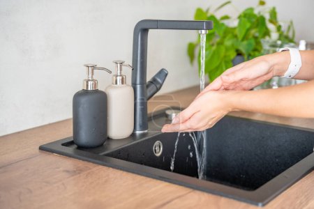 A woman washes hands and uses soap from reusable bottle. Eco-friendly lifestyle. High quality photo