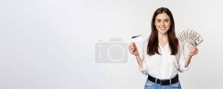 Foto de Portrait of woman standing with cash and credit card, concept of money, microcredit and loans, standing over white background happy. - Imagen libre de derechos