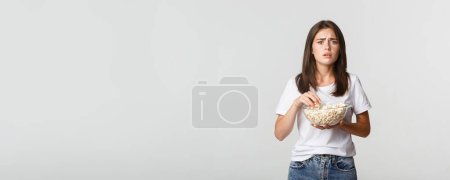Foto de Retrato de una joven compasiva viendo una película conmovedora, comiendo palomitas de maíz. - Imagen libre de derechos