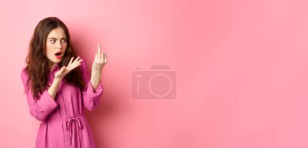 Photo for Annoyed girlfriend arguing about proposal, wants to get married, showing finger without engagement ring, standing confused against pink background. Relationship concept - Royalty Free Image