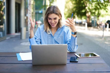 Young businesswoman, attend online video conference, writing down, working, taking notes in her documents, sitting outside on fresh air.
