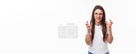 Photo for Waist-up of hateful and pissed-off, annoyed young female telling about person she hates, clench hands into fists, cursing, swearing at guy, want strangle someone from annoyance, white background. - Royalty Free Image