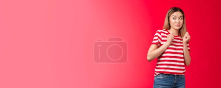 Photo for Alarmed silly blond asian girl wear striped t-shirt stay away suspicious person, press hands chest reluctant aversion, tilt back displeased hesitant express dislike shock, stand red background. - Royalty Free Image