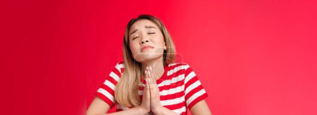 Photo for Close-up silly hopeful asian girl blond hairstyle, asking god help, hold hands pray, supplicating raise head up closed eyes, making wish, anticipating miracle, pleading lord dream come true. - Royalty Free Image