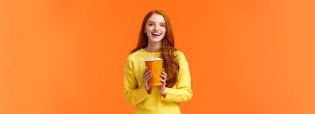 Photo for Cheerful cute redhead curly girlfriend holding popcorn chat with boyfriend before movie start at cinema, smiling joyfully, like attend premieres in theatres, standing overjoy orange background. - Royalty Free Image