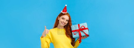 Photo for Girl can wrap your gift easily. Pleased and assertive pretty redhead female shop assistant help out customer, showing thumb-up, all done or good gesture, smiling holding box of present. - Royalty Free Image