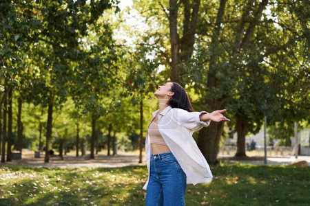 Photo for Carefree asian girl dancing, feeling happiness and joy, enjoying the sun on summer day, walking in park with green trees. - Royalty Free Image