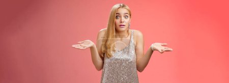 Photo for Unsure clueless awkward attractive blond european woman in silver glamour dress shrugging hands sideways widen eyes raise eyebrows unaware no idea what happening, standing questioned confused. - Royalty Free Image