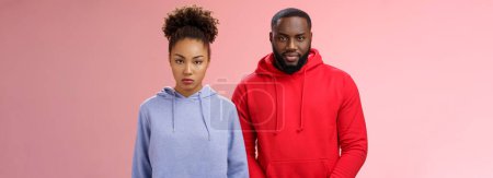 Photo for Two cute african american siblings standing together pink background invited family dinner greet new mom boyfriend, sister look displeased serious brother smug have idea prank stepdad. - Royalty Free Image