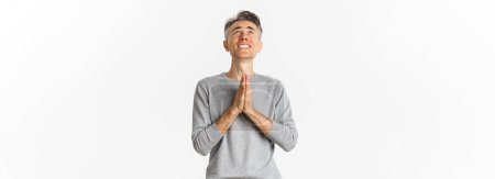 Photo for Image of nervous middle-aged man begging God, looking up and pleading for something, supplicating over white background. - Royalty Free Image