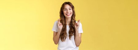 Photo for Girl faithfully believe dream come true hopefully awaiting positive results smiling broadly cross fingers good luck implore god good news stand excited optimistic yellow background. - Royalty Free Image
