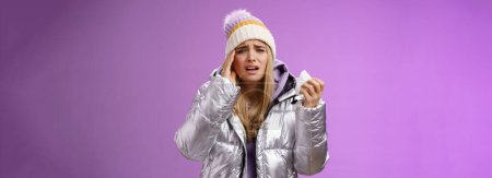 Photo for Lifestyle. Ill upset sobbing cute blond girl feel unwell hold napkin tissue touching head temple frowning grimacing painful migraine got sick during winter vacation walking outdoor headache - Royalty Free Image