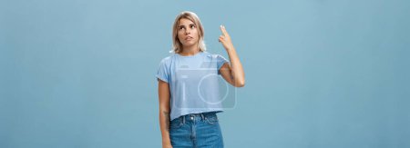 Photo for Stop teaching me how live my life. Portrait of irritated displeased attractive blonde female in denim shorts and casual t-shirt rolling eyelids from annoyance showing gun gesture as if blowing brains. - Royalty Free Image