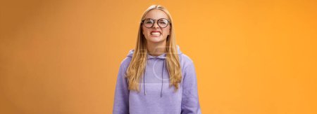 Photo for Blond girl show teeth warn can stand herself bite, fool around grimacing funny wearing purple hoodie glasses standing orange background better not mess with me, pranking friend have fun. - Royalty Free Image