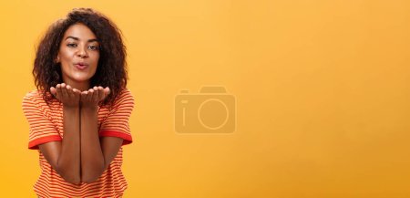 Foto de Enviar un beso apasionado a la persona más cariñosa. Romántico atractivo y elegante novia afroamericana joven con peinado rizado flexión hacia la cámara con una ligera sonrisa, labios doblados soplando mwah - Imagen libre de derechos