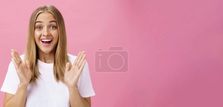 Photo for Woman learning awesome great news clasping hands in joy and excitement rejoicing feeling hapyp for friend smiling broadly and looking cheerful at camera with amused expression over pink background - Royalty Free Image