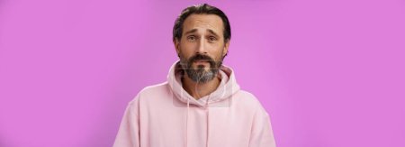 Photo for Upset worried unconfident adult bearded caucasian man grey hair frowning look hopefully nervously waiting important news, standing anxious hesitant unhappy, standing purple background unwell. - Royalty Free Image