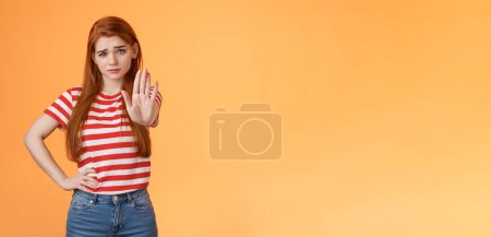 Photo for Time to stop. Serious-looking displeased bossy confident redhead girl extend arm in prohitibion, forbidden gesture, smirk disbelief and doubtful, warn not trespass, stand orange background. - Royalty Free Image