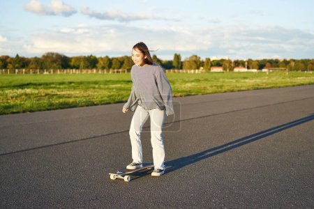 Téléchargez les photos : Loisirs et mode de vie. Jeune femme en skateboard. Skater fille profiter de croisière sur longboard par jour ensoleillé en plein air. - en image libre de droit