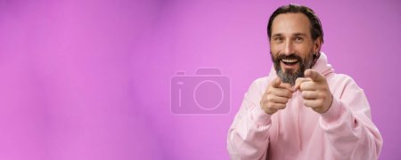 Photo for Funny amused carefree happy adult handsome man pranking friend fool around pointing camera index fingers greeting choosing you laughing joyfully having fu, standing purple background rejoicing. - Royalty Free Image