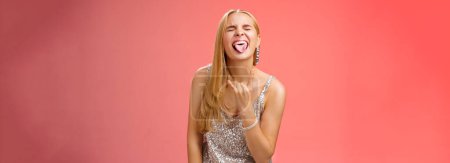 Photo for Lifestyle. Excited carefree entertained blond in silver glittering evening dress partying having fun amused show tongue close eyes rock-n-roll gesture heavy metal enjoying awesome celebration - Royalty Free Image