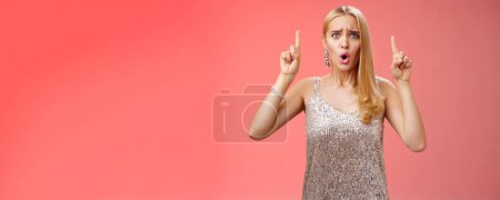 Photo for Upset gloomy complaining blond whining girl in silver stylish luxurious dress frowning cringing unhappy pointing up regret jealous tell boyfriend sale over, standing depressed sad red background. - Royalty Free Image