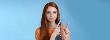Photo for Assertive good-looking redhead girl know what talking about pointing upper left corner index fingers showing confidently good product recommend check out standing blue background. Copy space - Royalty Free Image