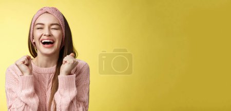 Foto de Aliviado feliz triunfante atractiva mujer europea con suéter de punto rosa gritando sí satisfecho, levantando los puños en la victoria ojos cerrados sonriendo, celebrando la victoria, sintiéndose afortunado escuchando buenas noticias. - Imagen libre de derechos