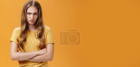 Photo for Girl mad like devil. Portrait of angry bothered and offended hateful young woman looking from under forehead frowning and sulking crossing arms against chest in defensive pose, scorning offender. - Royalty Free Image
