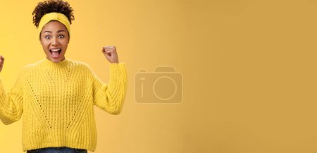 Téléchargez les photos : Oui, enfin le mien. excité surpris amusé afro-américain fille célébrant victoire achivement acclamations souriant largement crier repos poings triompher succès, debout fond jaune. - en image libre de droit