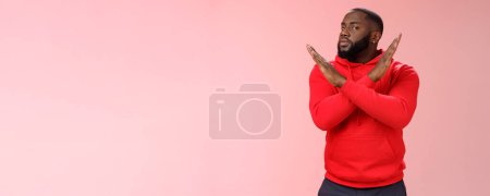 Téléchargez les photos : Arrête ça. Portrait homme afro-américain sérieux assistant montrer geste croisé dire finir de refuser, rejeter l'offre ne va jamais le faire, debout hésitant fond rose réponse négative. - en image libre de droit