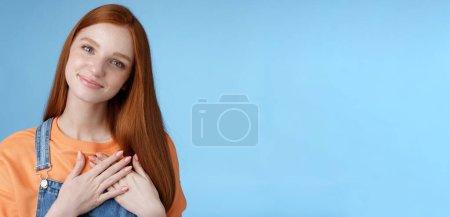 Photo for Touched romantic tender cute redhead feminine girl blue eyes tilting head melting heartwarming gesture receive gladly pleasant prest touch heart smiling grateful, feel romance love, blue background. - Royalty Free Image