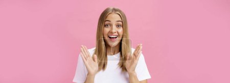 Photo for Woman learning awesome great news clasping hands in joy and excitement rejoicing feeling hapyp for friend smiling broadly and looking cheerful at camera with amused expression over pink background - Royalty Free Image