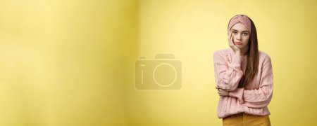 Photo for How boring. Indifferent upset gloomy girl missing party feeling bored leaning on palm reluctant, sad looking careless at camera visiting uninteresting lecture, suffering boredom over yellow wall. - Royalty Free Image