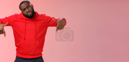 Photo for Cheeky stylish good-looking black bearded guy look cool tilting head bossy confident frowning seriously pointing down showing awesome place hang out homies, standing pink background. - Royalty Free Image