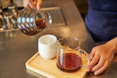 Téléchargez les photos : Gros plan des mains de barista femelle versant le café filtre dans la tasse, préparant l'ordre pour le client de café. - en image libre de droit