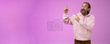 Photo for Fashionable good-looking fascinated mature bearded man grey hair look astonished pointing gazing upper left corner see miracle incredible breathtaking magnificanent view, standing purple background. - Royalty Free Image