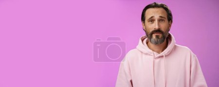 Photo for Upset worried unconfident adult bearded caucasian man grey hair frowning look hopefully nervously waiting important news, standing anxious hesitant unhappy, standing purple background unwell. - Royalty Free Image