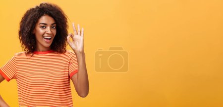Foto de Lo tengo, creo que está hecho. Retrato de mujer afroamericana tranquila y despreocupada con un peinado rizado levantando bien o un excelente gesto y sonriendo asegurando que sabe lo que hace - Imagen libre de derechos