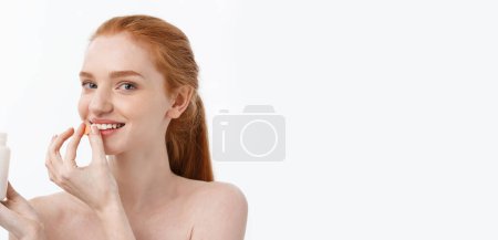 Portrait of good-looking young caucasian woman holding pills, trying to take care of immune system and health over gray background