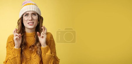 Photo for Worried cute girl nerd hope pass exam standing nervous cross fingers good luck frowning grimacing look up praying supplicating anticipating results anxiously, wearing glasses, yellow background. - Royalty Free Image