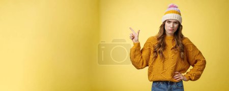 Photo for Meh lame promo. Portrait picky arrogant unimpressed complaining female fashionable customer pointing upper left corner frowning cringing displeased unsatisfied, dislike bad offer, yellow background. - Royalty Free Image