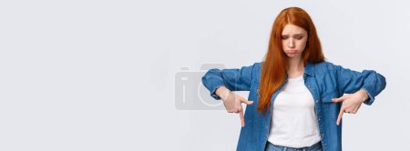 Photo for Upset, gloomy timid redhead teenage girl express pity or jealousy, regret something broken, sobbing, pouting sad and looking pointing down distressed, standing unhappy over white background. - Royalty Free Image