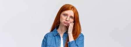 Photo for Close-up portrait gloomy unhappy redhead sad girl in glasses, teenager having bad day at college, leaning on hand pouting and sobbing, feeling hurt and distressed, standing depressed white background. - Royalty Free Image