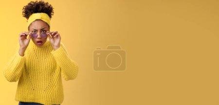 Téléchargez les photos : Choqué sans voix impressionné afro-américain. élégant collègue femme goutte mâchoire regard étonné décoller lunettes de soleil élargir les yeux ne peuvent pas croire confus debout fond jaune questionné caméra regard. - en image libre de droit