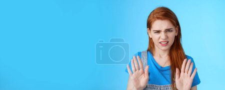 Photo for Close-up uninterested displeased ignorant picky redhead girlfriend, frowning make disgusted grimace raise hands block stop gesture, refuse, waving arms no rejection sign, stand blue background. - Royalty Free Image