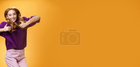 Téléchargez les photos : Optimiste et joyeux gingembre lumineux fille sautant heureux et joyeux avoir du plaisir à montrer pouces vers le haut comme et l'approbation donnant un retour positif de super cool idée ou concept sur le mur orange - en image libre de droit
